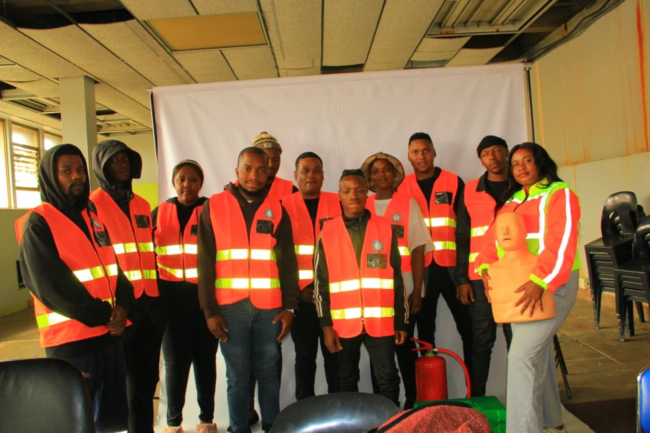 Learners in safety vests with first aid training dummy